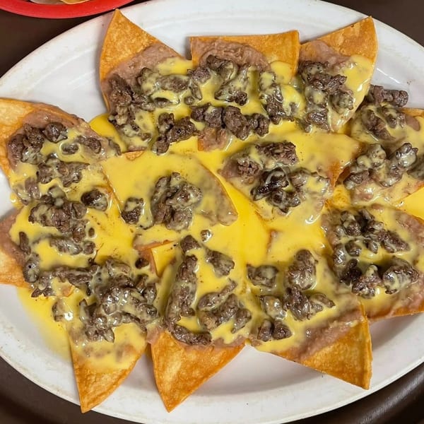 Close-up of Tequila Lopez Mexican Restaurant's nachos with melted cheese, refried beans, and steak.