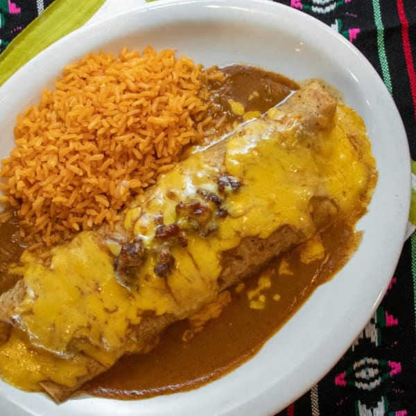 A Tequila Lopez Mexican Restaurant burrito covered in melted cheese and sauce, served with orange rice.